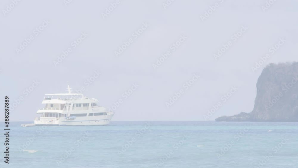 A cruise is anchored near an island of the Galapagos islands. The cruise is on a paradisiac beach with a clear and turquoise water ocean. A cruise is anchored near an island of the Galapagos islands. The cruise is on a paradisiac beach with a clear and turquoise water ocean.