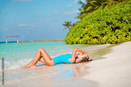 Full size profile side photo of slim figure charming stunning girl tourist enjoy bay exotic weekend chilling lie sand sun bath wear bodysuit