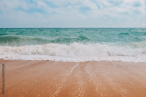 Turquoise waves with foam on the sandy shores of benagil beach in portugal.