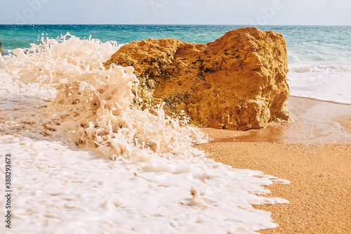 Waves crash on rocks on the sandy shores of benagil beach in portugal