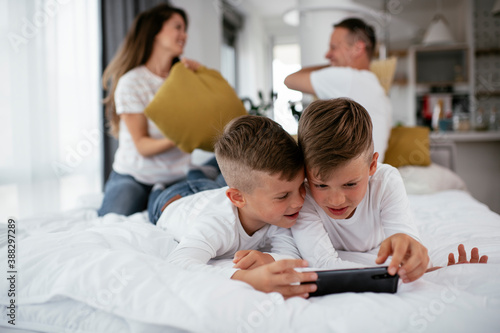 Two little brothers are playing games on the phone. Beautiful boys enjoying at home.