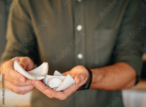 A man shows a broken ceramic white cup in the kitchen. Quarrel or carelessness concept.