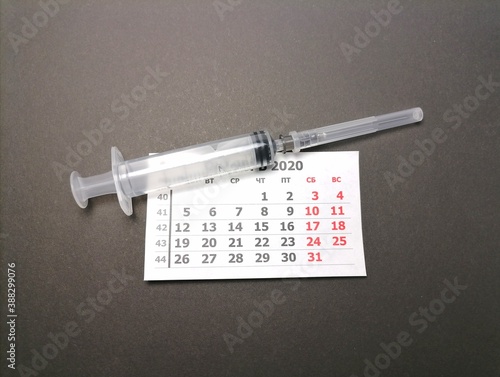 calendar and syringe on black background