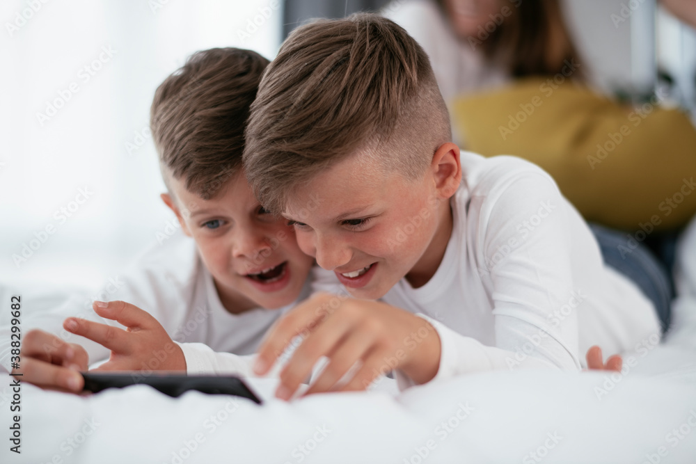 Two little brothers are playing games on the phone. Beautiful boys enjoying at home. Two little brothers are playing games on the phone. Beautiful boys enjoying at home.