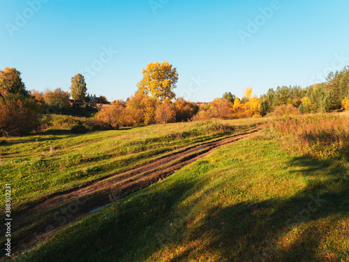 Autumn rural road landscape. Autumn forest path through the field. Road track in rural areas. Natural background or screen saver