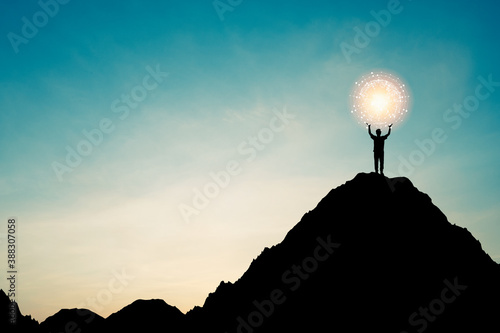 Silhouette of businessman holding world and connection line on the top of mountain with over blue sky and sunlight. It is symbol of leadership successful achievement with goal and objective target. photo