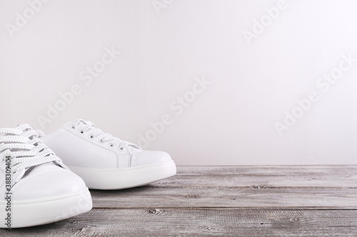 White leather casual sneakers on wooden background, copy space