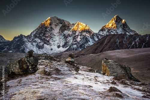 Taboche (6,495m) and Cholatse (6,440m) mountains in early morning which peaks lightened with sun beams. Big rocks are on the foreground. The Himalaya mountains. Nepal. photo