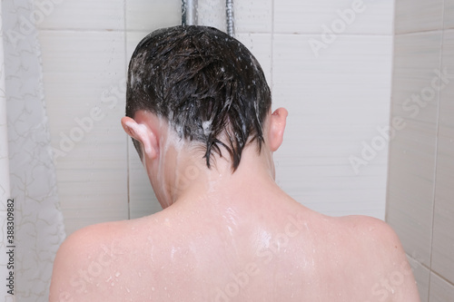 Hygienic procedures and healthy habits of a preteen boy - taking shower and washing hair with shampoo
