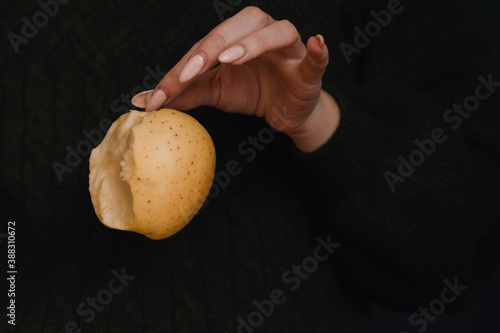 A bitten apple in the palm of your hand. Green background. Beautiful manicure.