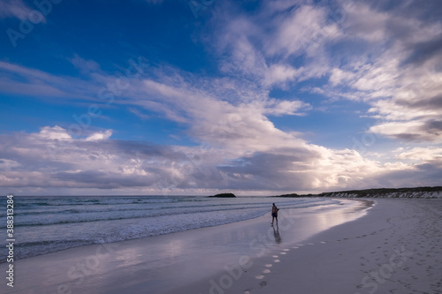 The sun starts to set and the colors in the sky starts to change. The colors at Tortuga Bay beach starts to saturate. A person walking on the shore can be see in the foreground. Isabela Island, Galapa photo