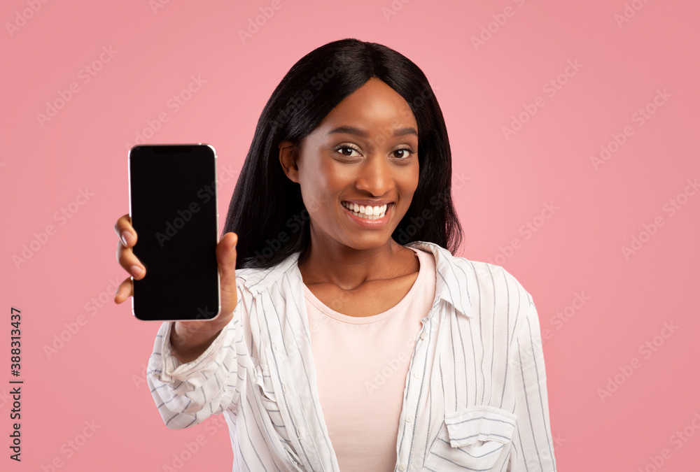 Pretty black woman showing mobile phone with space for your app design, pink studio background Pretty black woman showing mobile phone with space for your app design, pink studio background