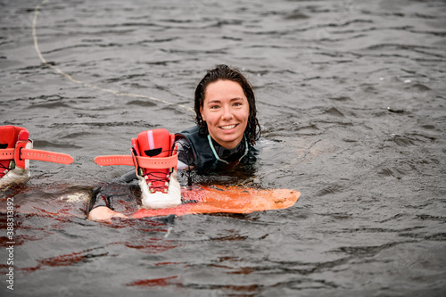 smiling young woman swims in the water in vest with bright wakeboarding board photo