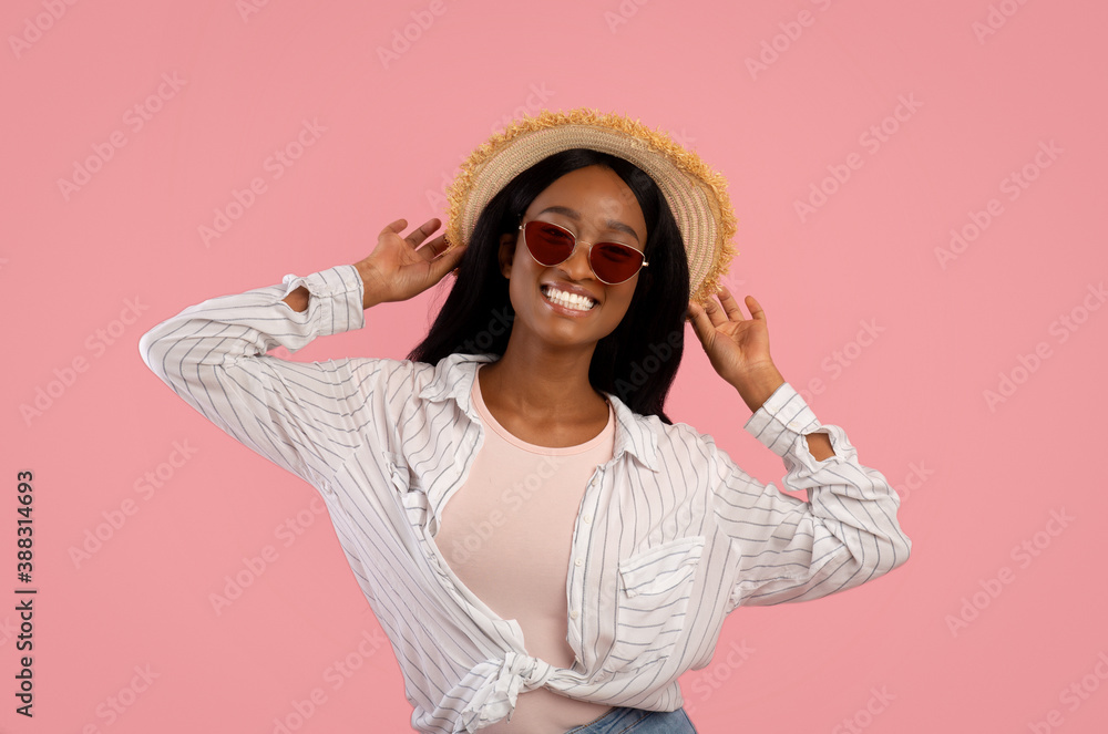 Portrait of gorgeous black woman in straw hat and sunglasses posing on pink studio background Portrait of gorgeous black woman in straw hat and sunglasses posing on pink studio background