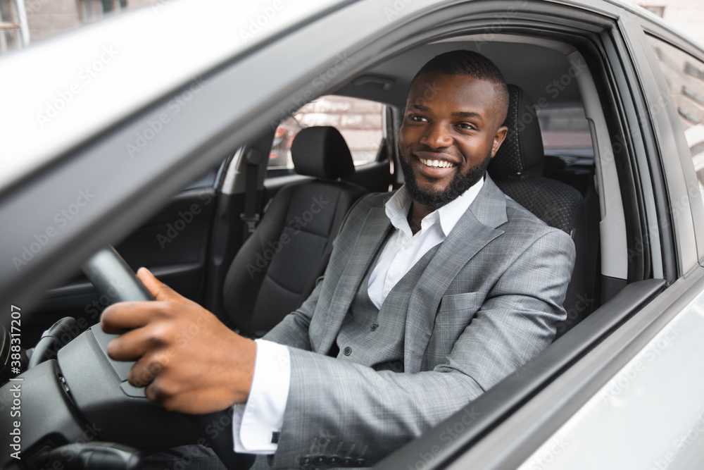 Smiling young black businessman driving luxury car Smiling young black businessman driving luxury car