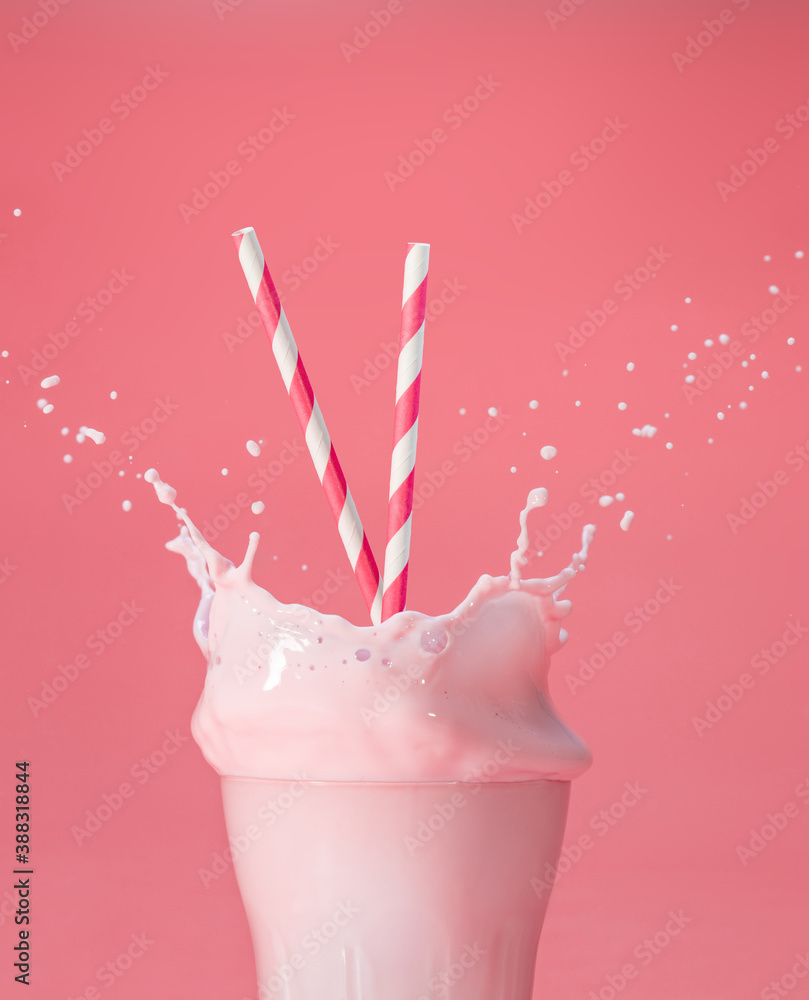 striped straws in a glass of splashing strawberry milkshake isolated on ...