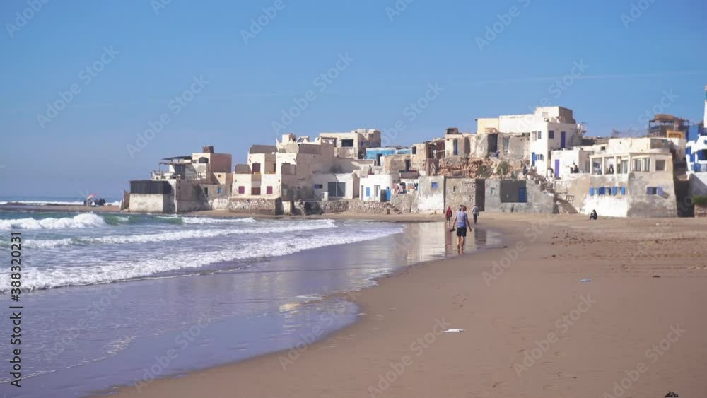 Tourists walk on the sand beach in small Morocco town in Sunny Summer Holiday Vacation in Africa Ocean Coast
Tourists walk on the sand beach in small Morocco town in Sunny Summer Holiday Vacation in Africa Ocean Coast