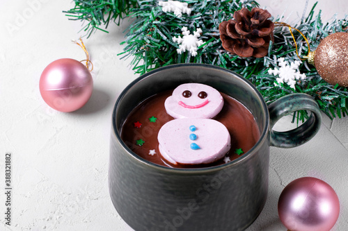 Cute marshmallow snowman floating on top of hot chocolate. Christmas dessert in the green ceramic mug