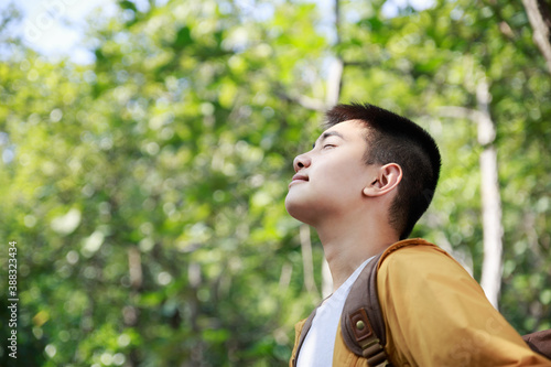 Asian teenager breathing deeply fresh air in a forest.