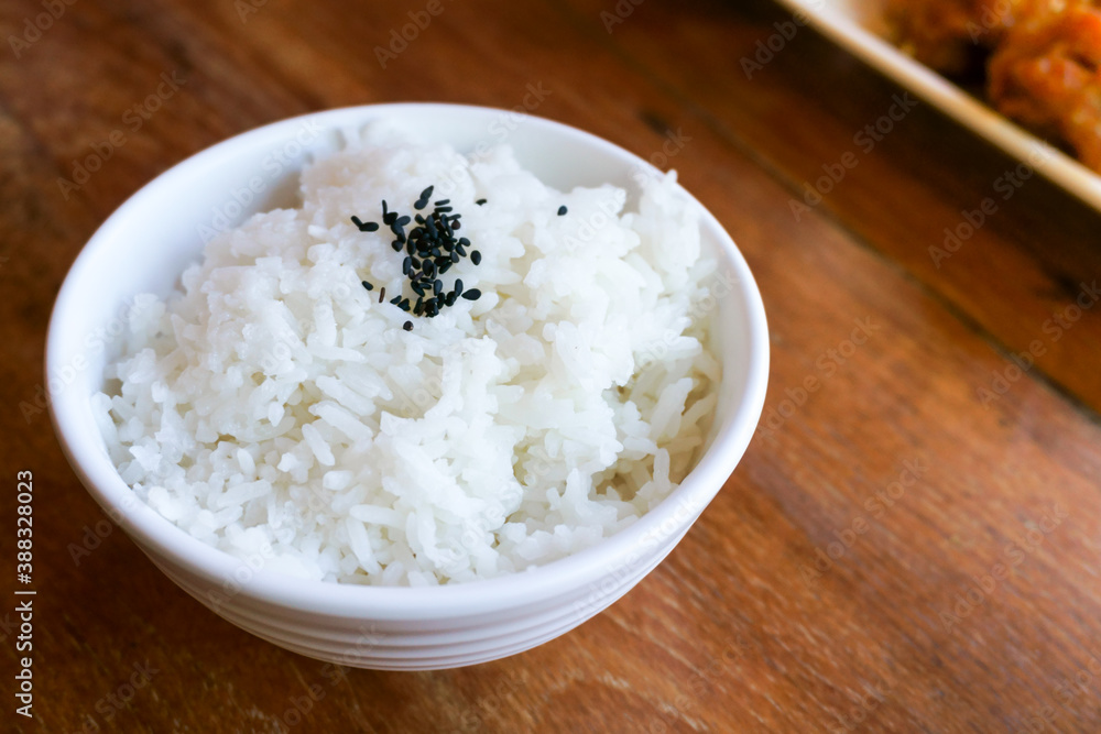 Rice in white cup on wood background and black sesame Rice in white cup on wood background and black sesame