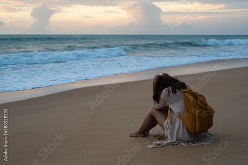 Unhappy Asian woman sitting alone on the beach. Sad, disappointed concept. Copy space