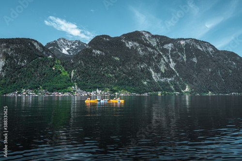 3 young guys sitting in a canoe in front of hallstatt city in austria on hallstattersee lake