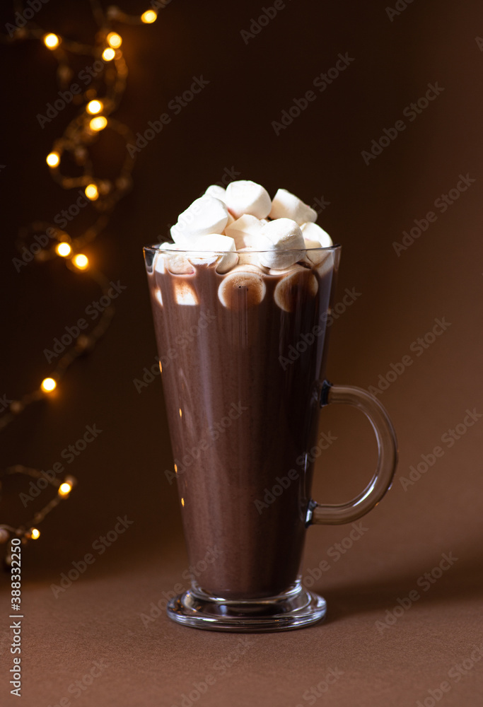 Cocoa drink with marshmallows in a glass on a brown background with festive winter decorations. Winter mood. Minimalistic monochrome composition. Selective focus. Frontal view. Vertical. Copy space Cocoa drink with marshmallows in a glass on a brown background with festive winter decorations. Winter mood. Minimalistic monochrome composition. Selective focus. Frontal view. Vertical. Copy space