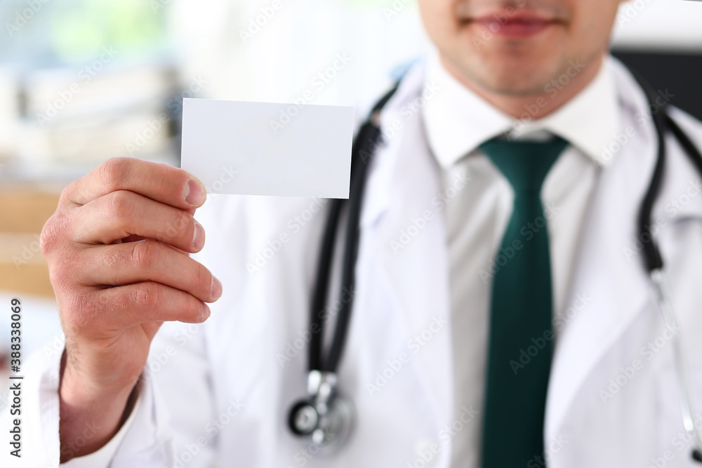 Male physician hand holding and giving white blank calling card closeup in office. Contact information exchange, introducing gesture at formal meeting, success, personal or family doctor concept Male physician hand holding and giving white blank calling card closeup in office. Contact information exchange, introducing gesture at formal meeting, success, personal or family doctor concept