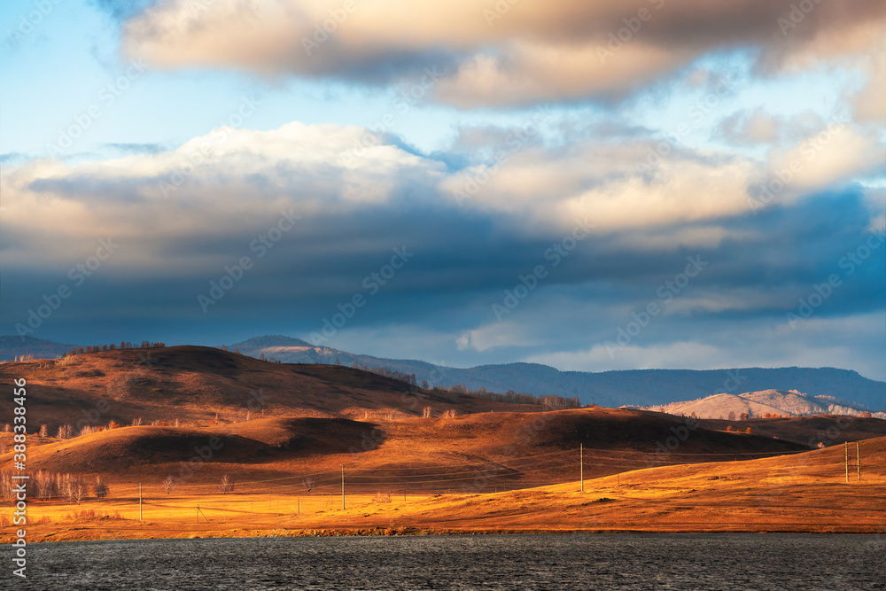 Yellow autumn hills on the shore of lake at sunset. Beautiful autumn landscape. South Ural, Russia