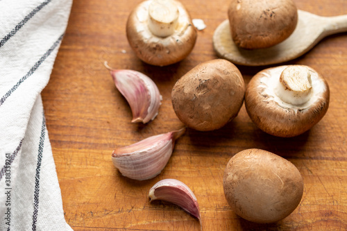 Aerial view of portobello mushrooms, garlic and kitchen towel, with selective focus, on wooden table, horizontal photo