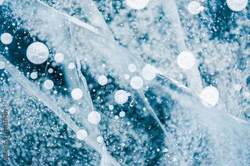 Texture of blue ice with cracks and air bubbles on the frozen lake. Macro image. Winter nature background