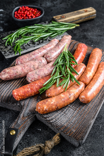 Assorted raw chorizo sausages on a wooden cutting board. Black background. Top view