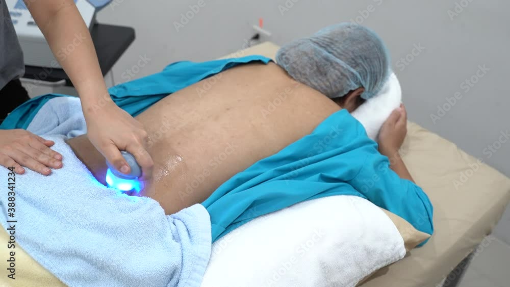 Medium shot of a physiotherapist applying ultrasound on the lower back of a female patient Medium shot of a physiotherapist applying ultrasound on the lower back of a female patient