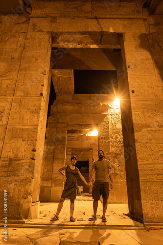 A couple of tourists between the columns at night of the temple of Kom Ombo in traditional dress, the temple dedicated to the gods Sobek and Horus. Town of Kom Ombo near Aswer, Egypt