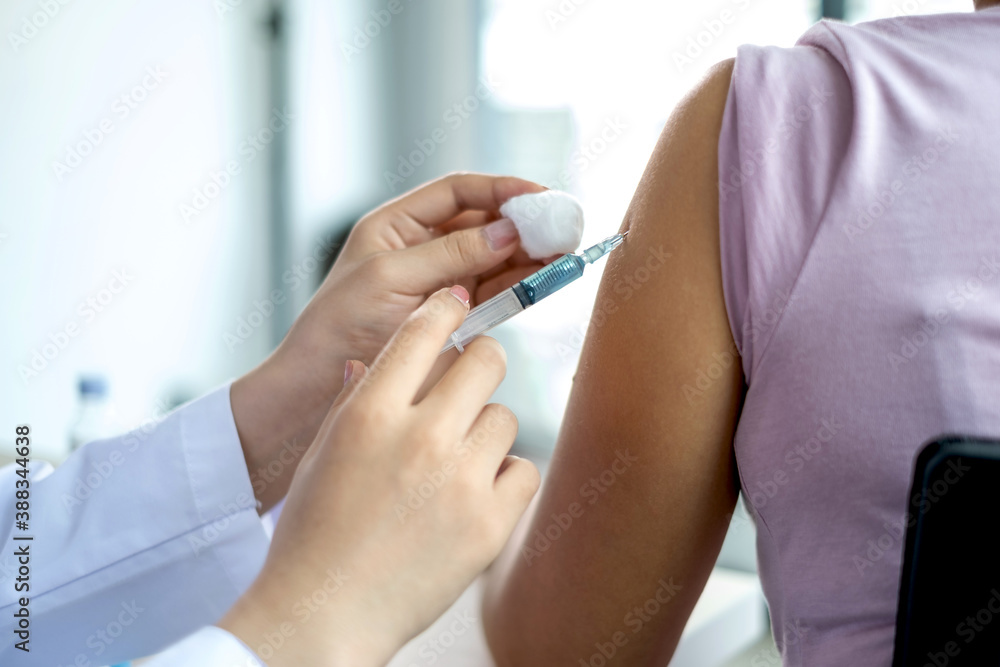The doctor's hand holding a syringe and was about to vaccinate a patient in the clinic to prevent the spread of the virus The doctor's hand holding a syringe and was about to vaccinate a patient in the clinic to prevent the spread of the virus