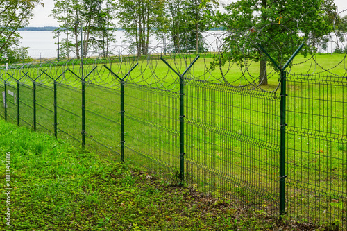 a metal fence of a military object with barbed wire