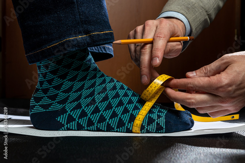 Shoe maker measures the feet of a client to create the perfect pair of classic shoes on a custom last