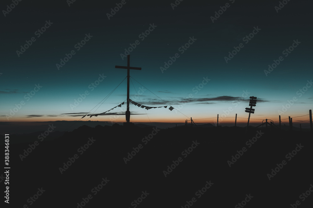 Obraz premium Gipfelkreuz am Riedberger Horn während dem Sonnenuntergang oder der blauen Stunde