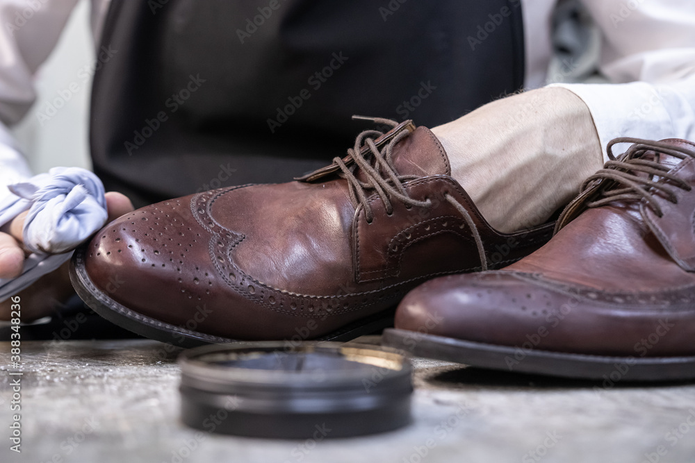 a man cleans a brown pair of shoes with a soft cloth and cream to a shine a man cleans a brown pair of shoes with a soft cloth and cream to a shine