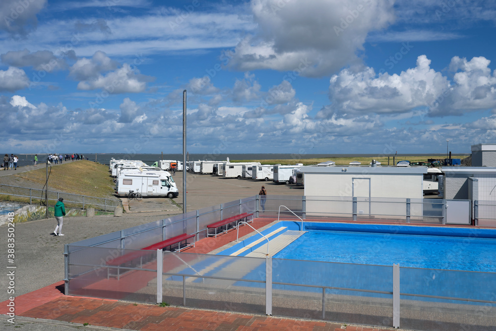 Blick über das Freibad von Harlesiel auf die Wohnmobil-Stellplätze am Hafen und Urlauber auf dem Deich an der Nordseeküste - Stockfoto Blick über das Freibad von Harlesiel auf die Wohnmobil-Stellplätze am Hafen und Urlauber auf dem Deich an der Nordseeküste - Stockfoto