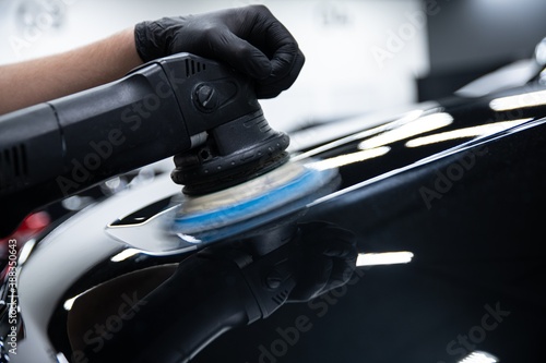 Car detailing studio worker renovating and polishing car paint photo