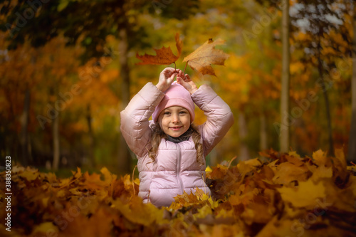  little girl having fun in the park in autumn leaves