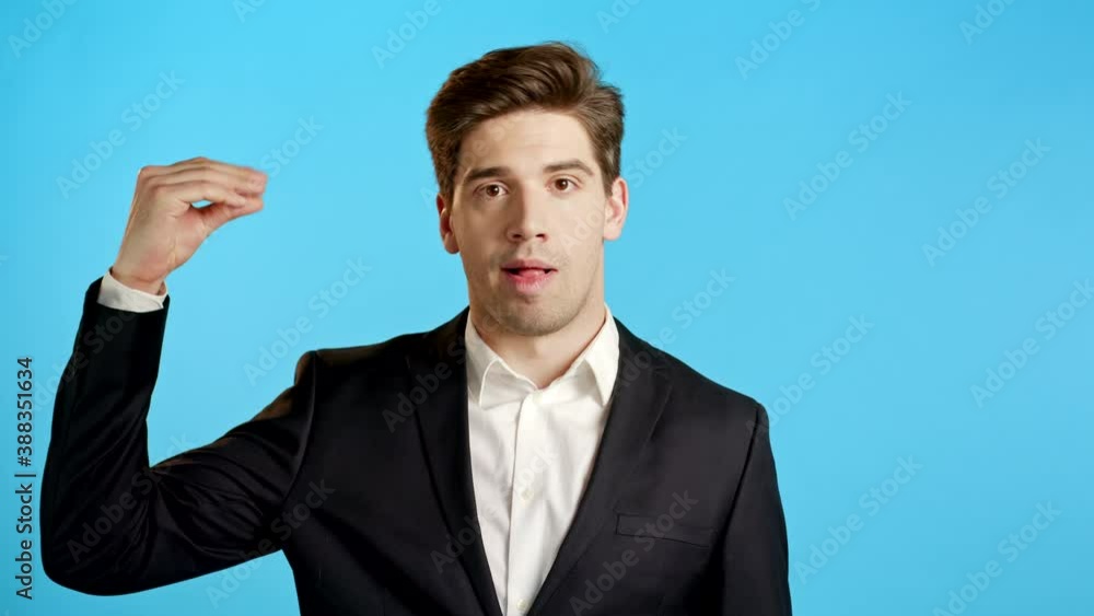 Handsome bored business man showing bla-bla-bla gesture with hands and rolling eyes isolated on blue background. Empty promises, blah concept. Lier Handsome bored business man showing bla-bla-bla gesture with hands and rolling eyes isolated on blue background. Empty promises, blah concept. Lier