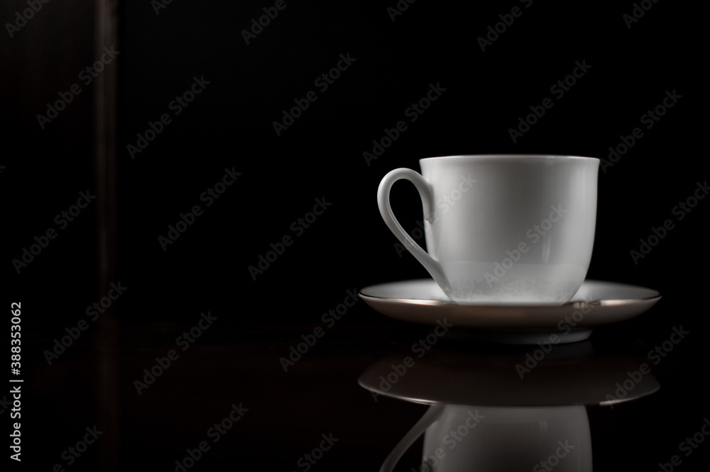 Obraz premium Noble white mug on a saucer on a dark background.