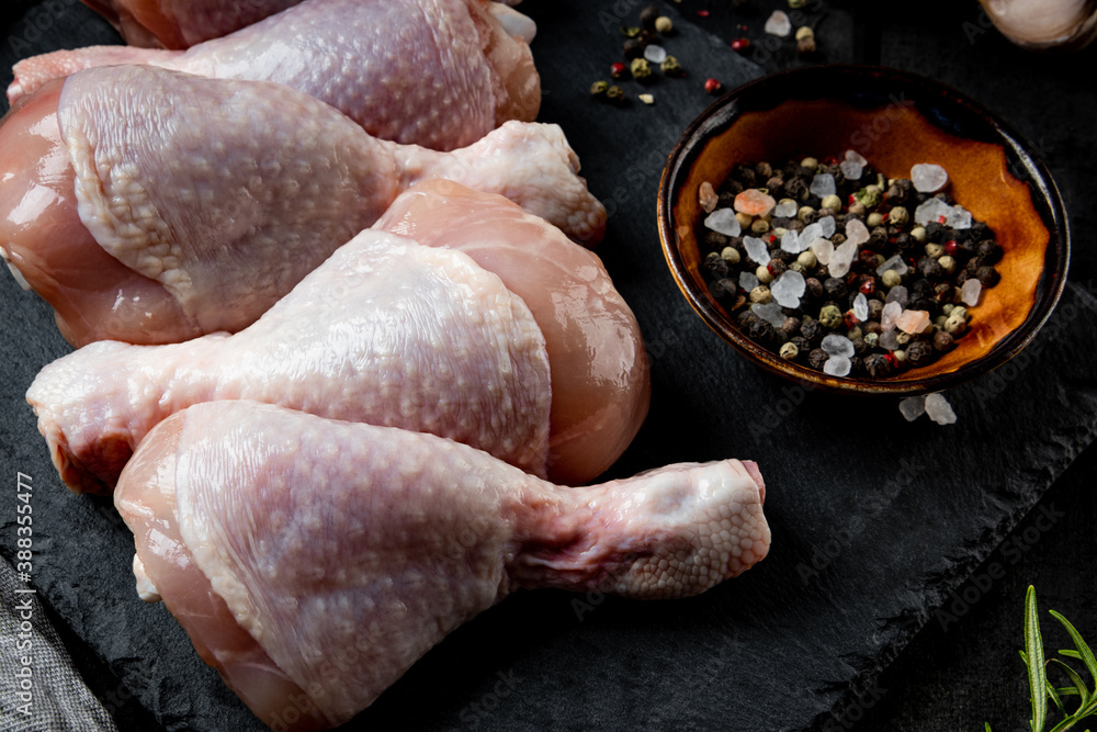 Raw chicken legs with spices on a black background close up Raw chicken legs with spices on a black background close up