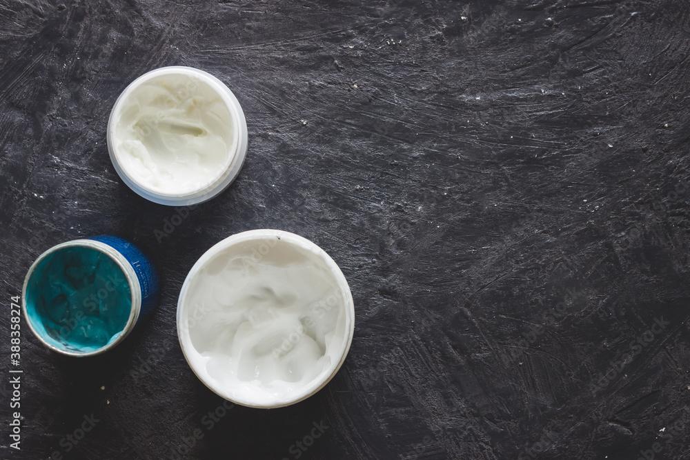 Top view of blue and white creams in jar. Hand creams and gel on dark grey background with copy space. Top view of blue and white creams in jar. Hand creams and gel on dark grey background with copy space.