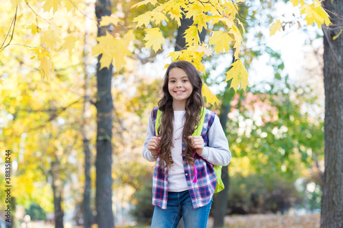 happy kid wear casual style. teen girl carry backpack on the way to school. child walk in autumn forest. fall leaves in park. seasonal weather. childhood happiness. beauty and nature