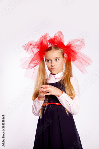 schoolgirl with bright tulle bows on her head in school clothes on a white background