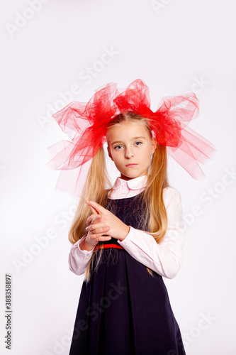 schoolgirl with bright tulle bows on her head in school clothes on a white background