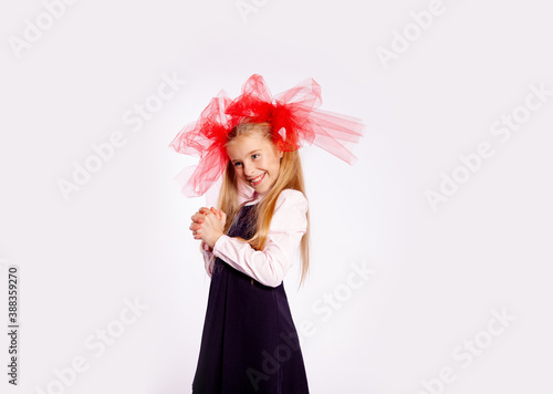 schoolgirl with bright tulle bows on her head in school clothes on a white background